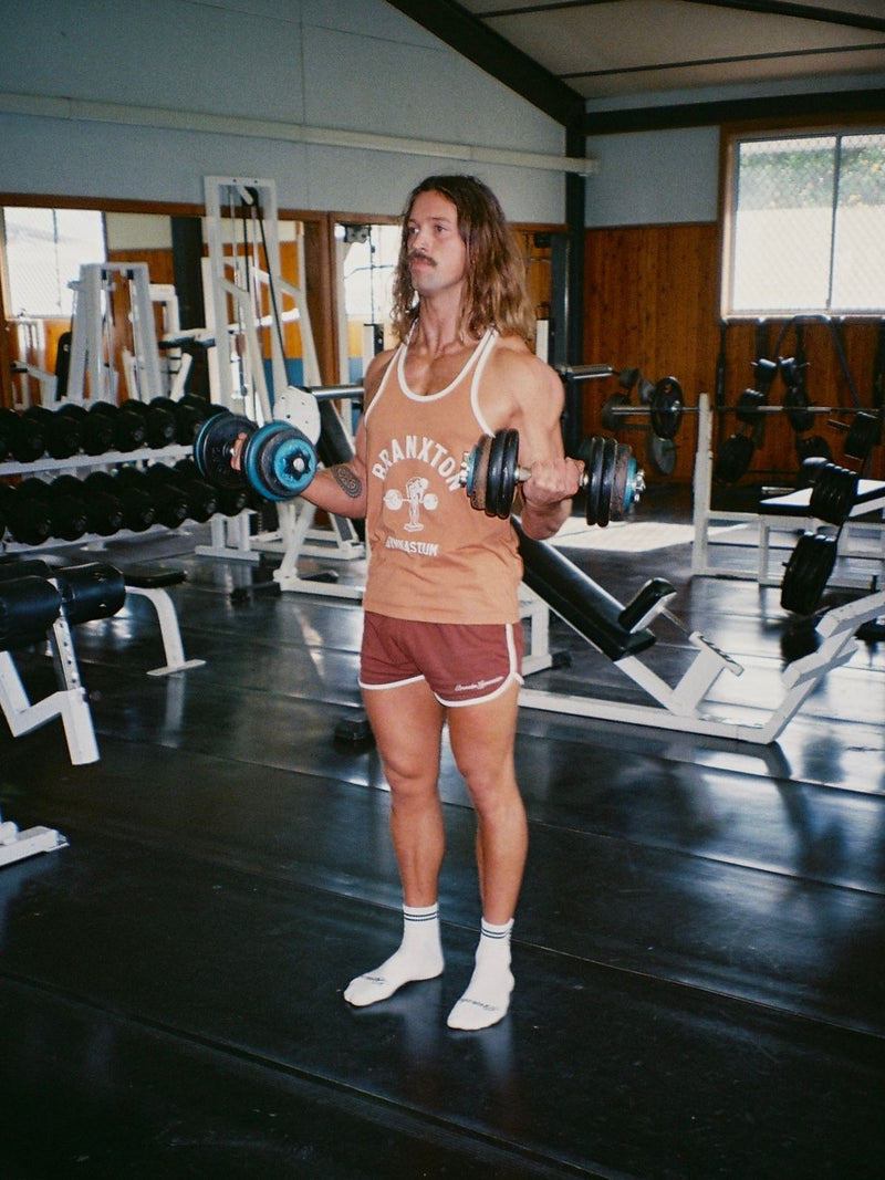 Person in a brown Barbell Row stringer in an old-school gym